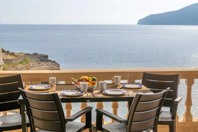 Outdoor dining area with a set table overlooking the sea.