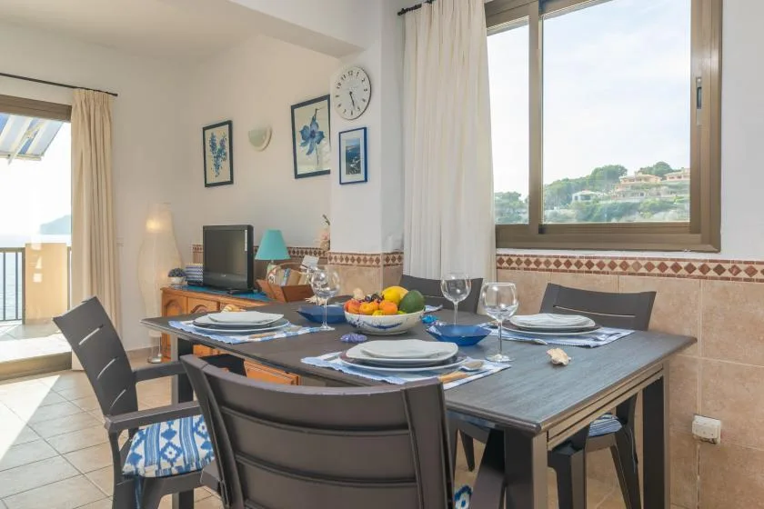 Comedor con la mesa puesta junto a una ventana grande.