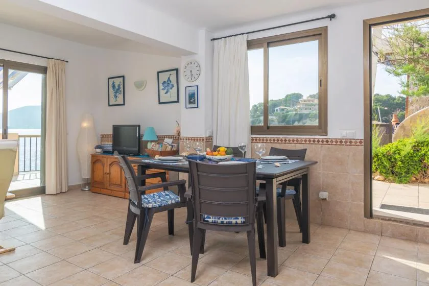 Un comedor con una mesa y sillas junto a grandes ventanas.