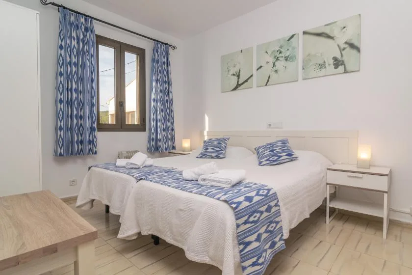 Un dormitorio con una cama bien hecha, cortinas estampadas azules y ropa de cama a juego.