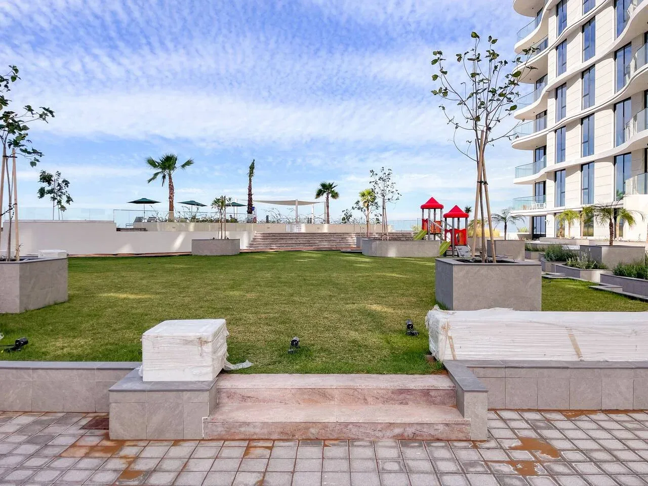Un patio ajardinado con césped, jardineras y un edificio moderno.