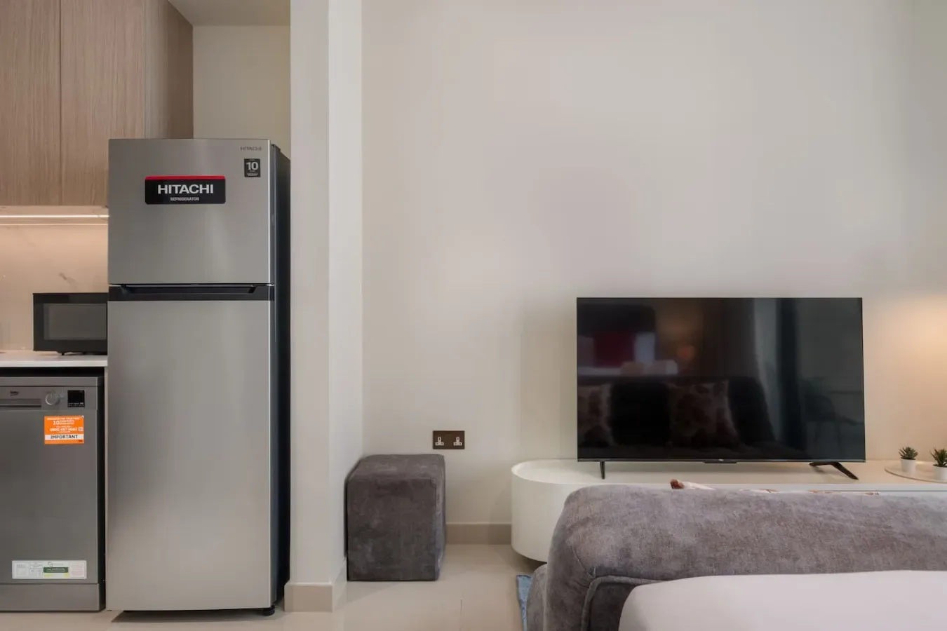 Una cocina compacta y sala de estar con refrigerador, televisor y asientos.