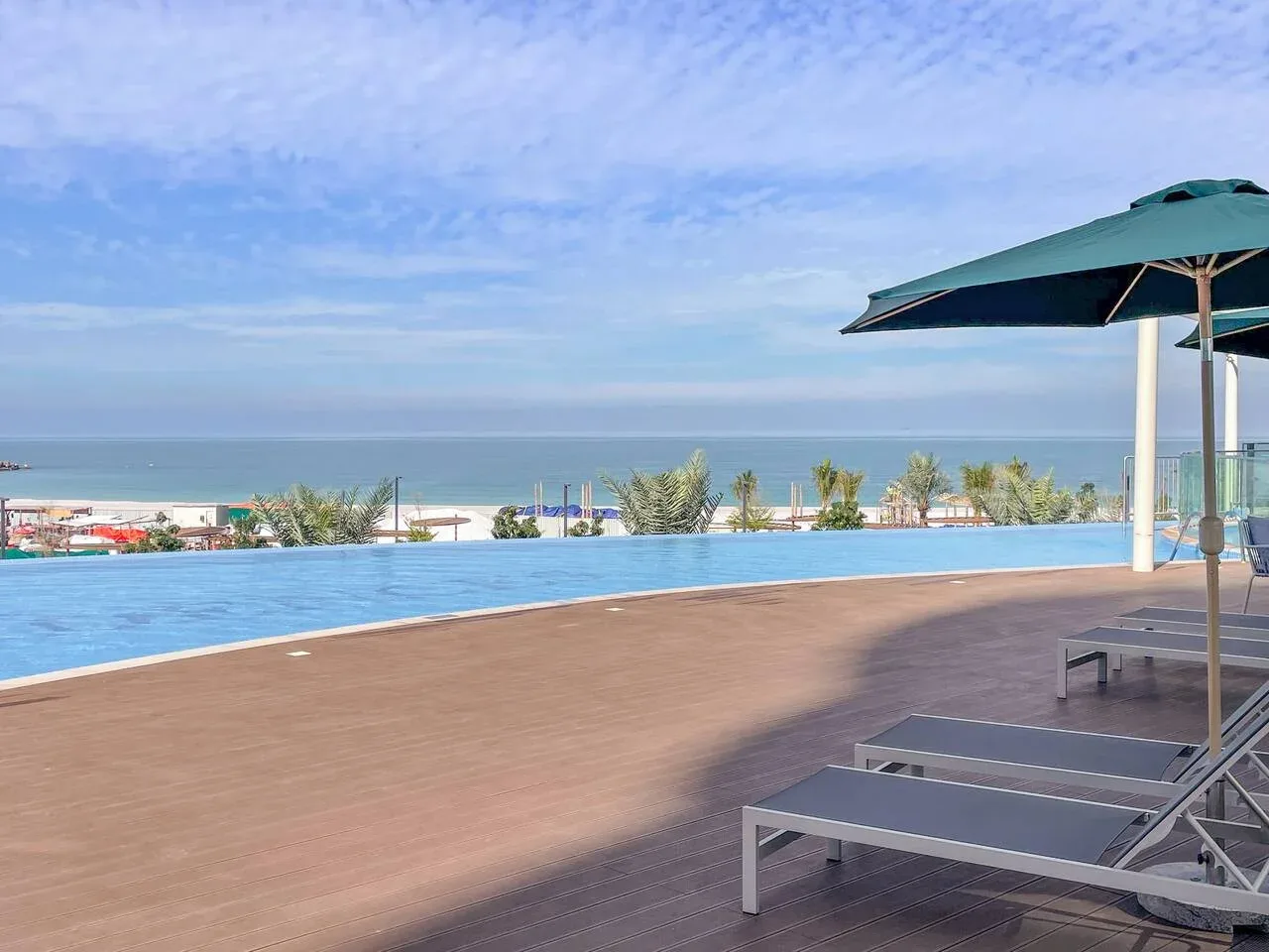 Una piscina al aire libre da al mar, con asientos junto a ella.