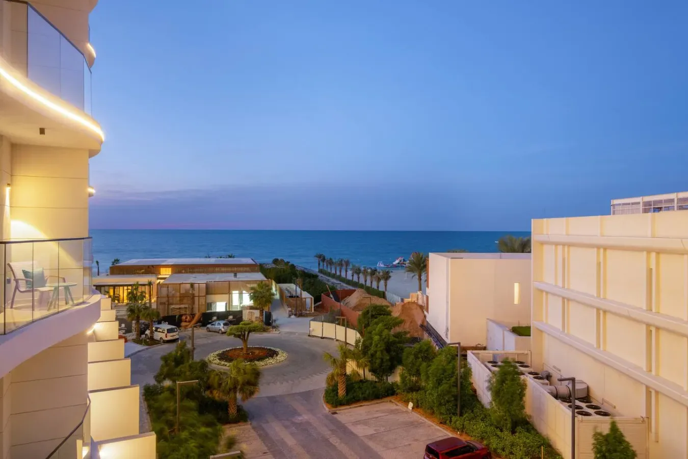 Un complejo hotelero costero mira al mar al atardecer, con jardines entre los edificios.