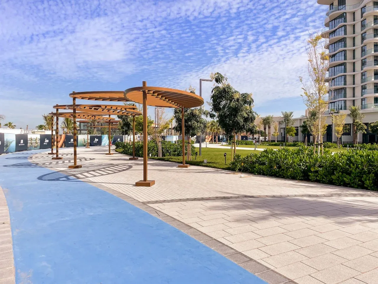 Un patio exterior ajardinado con un camino pavimentado y pérgolas de madera.