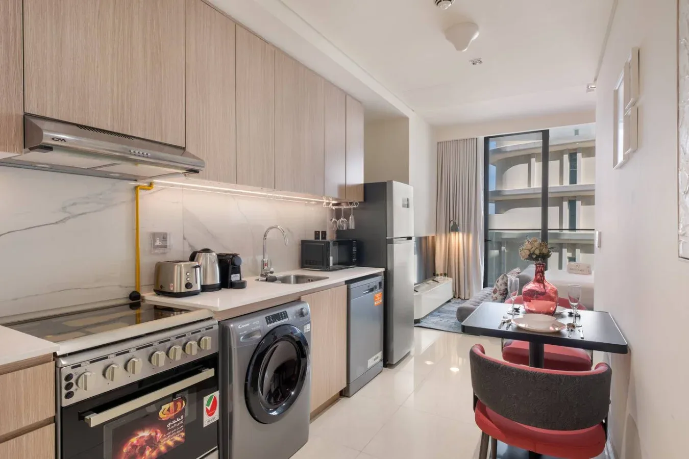Una cocina compacta se abre a un comedor junto a una ventana grande.