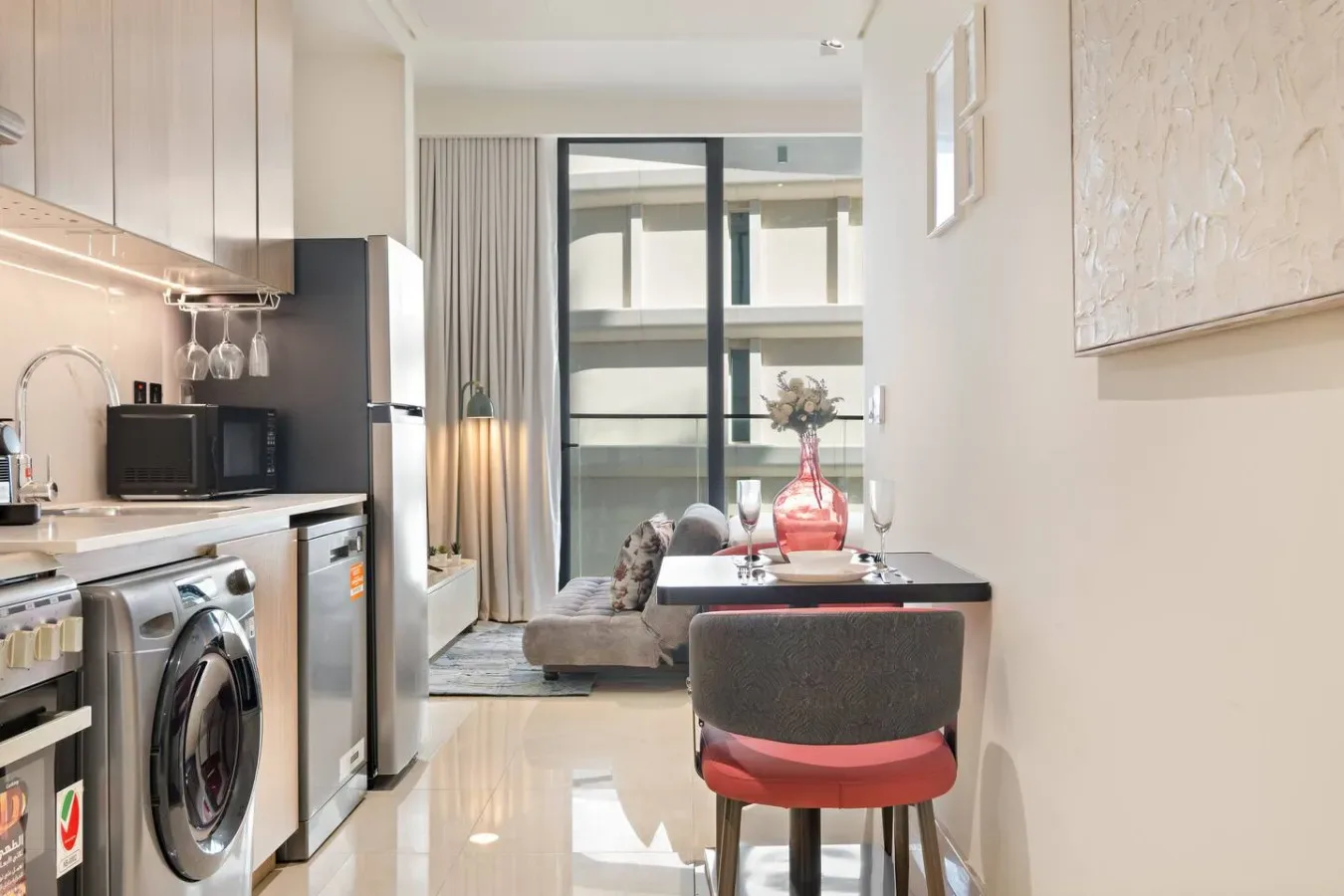 Una cocina compacta y zona de comedor se abren a una sala luminosa junto a grandes ventanales.