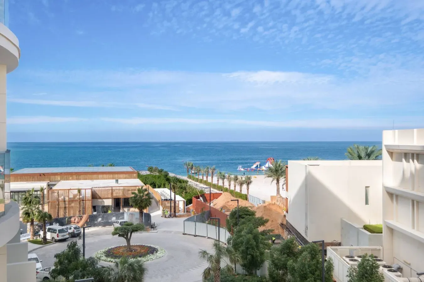 Un complejo costero da al mar, con palmeras y edificios modernos.