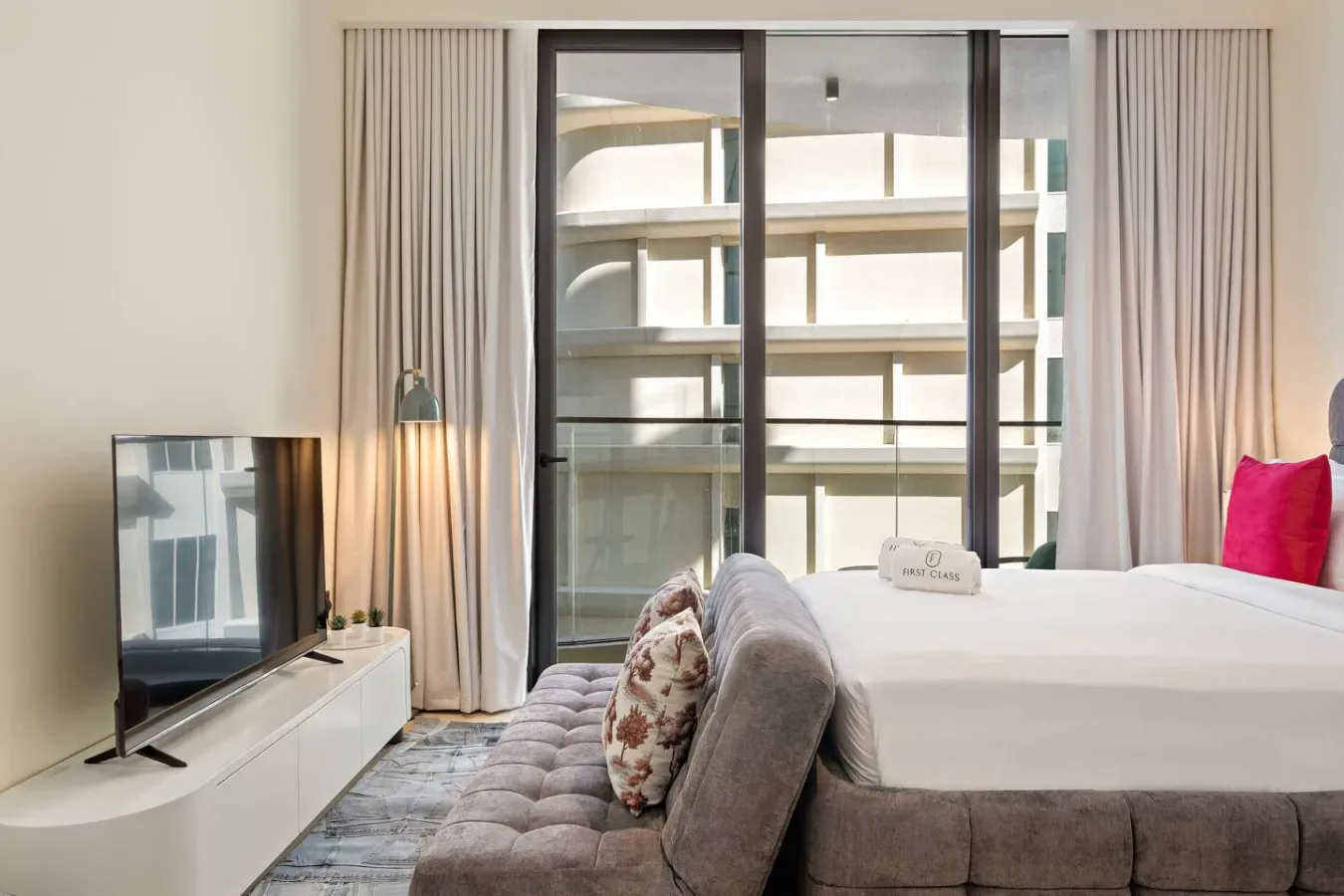 Un dormitorio con una cama grande junto a ventanales y cortinas.