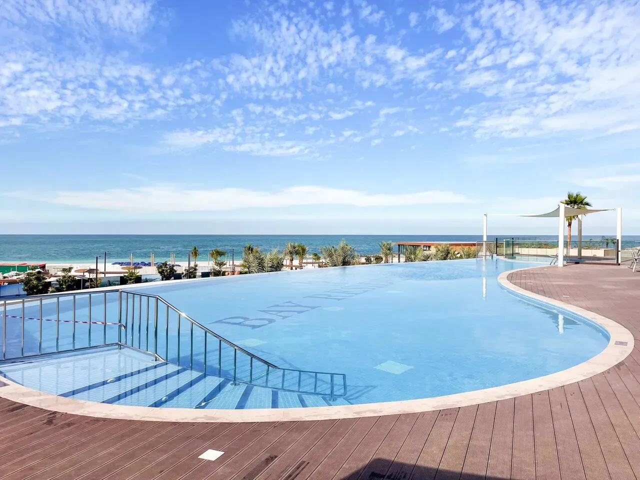 Una piscina al aire libre tiene vistas al mar bajo un cielo parcialmente nublado.
