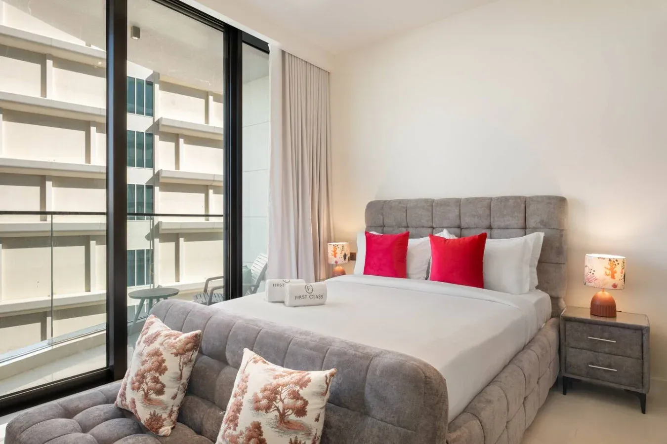 Un dormitorio con una cama bien tendida y ventanales de suelo a techo.