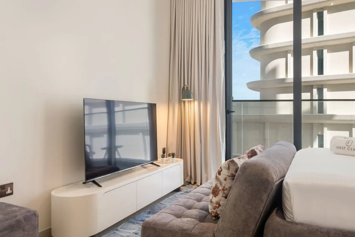 Dormitorio con un televisor sobre un mueble bajo junto a una ventana grande.