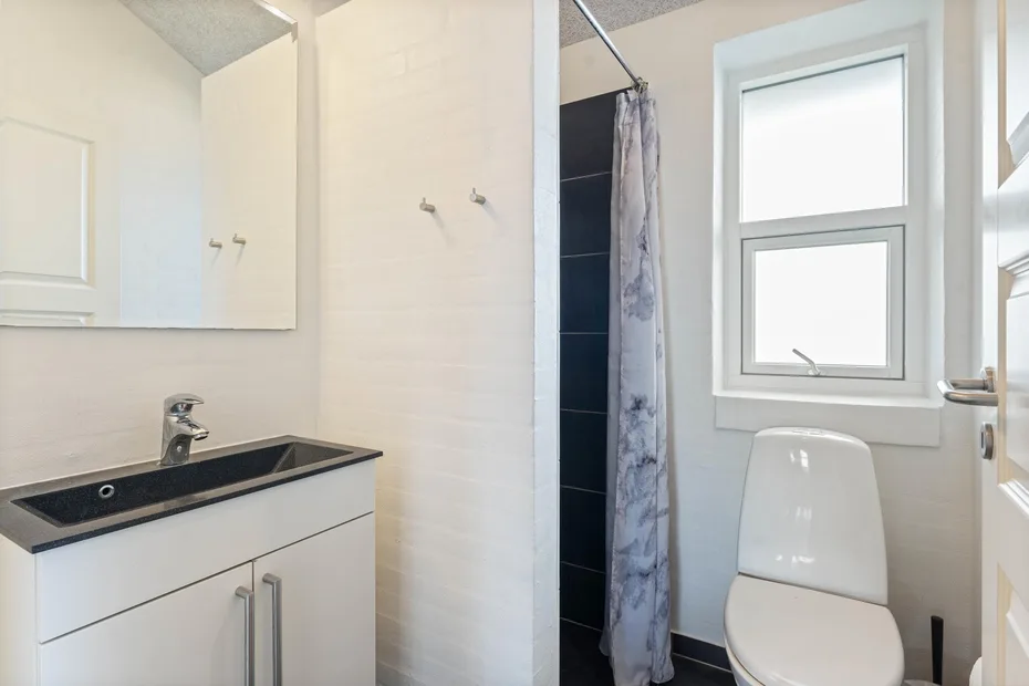 Un baño luminoso con lavabo, inodoro y ducha con cortina.