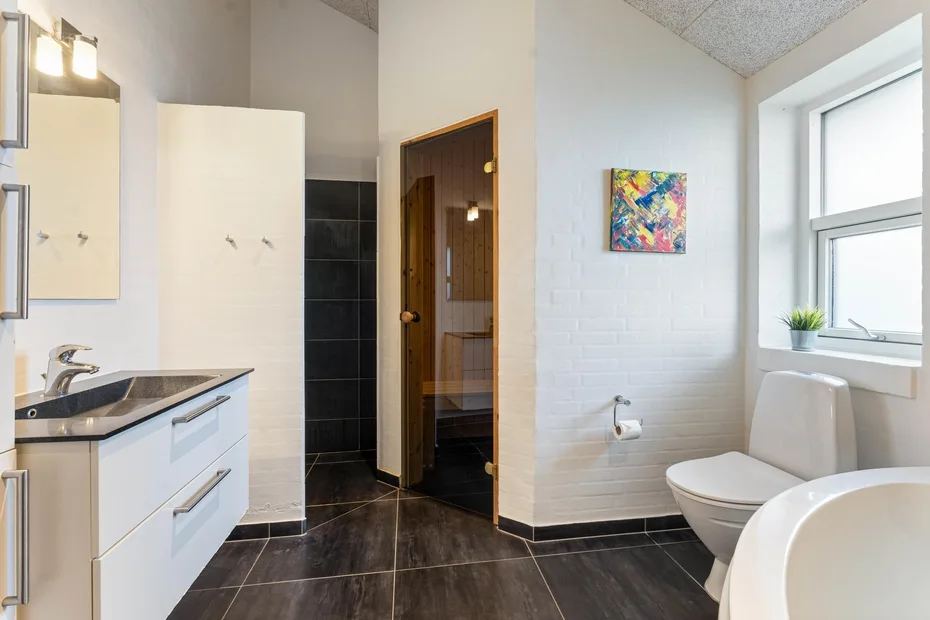 Un baño con lavabo, inodoro y una ventana grande.