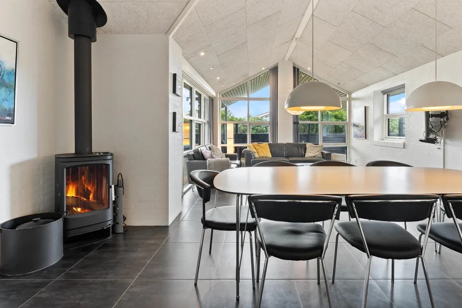 Un comedor y sala de estar diáfanos y luminosos, con una mesa y una chimenea encendida.