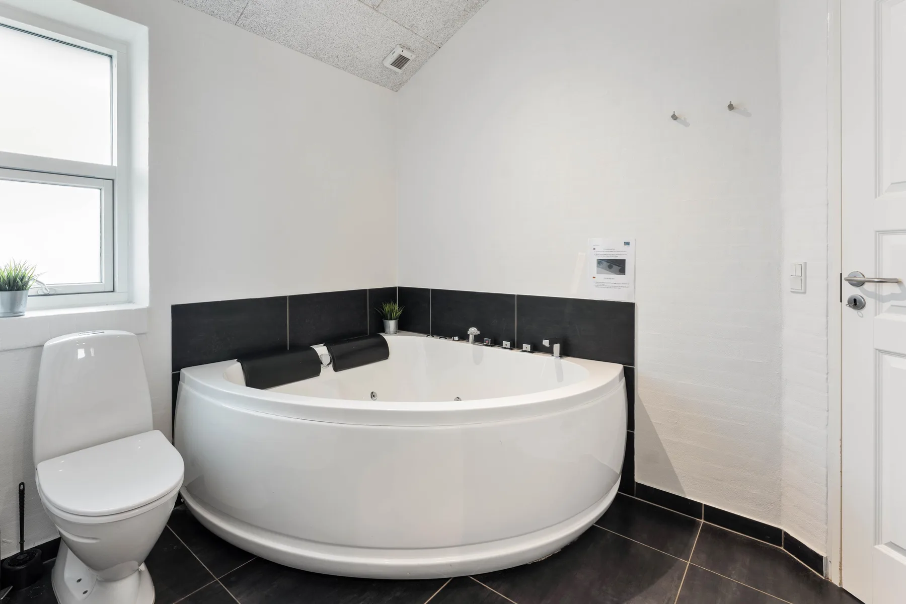 Un baño con una bañera grande y curva junto a un inodoro.