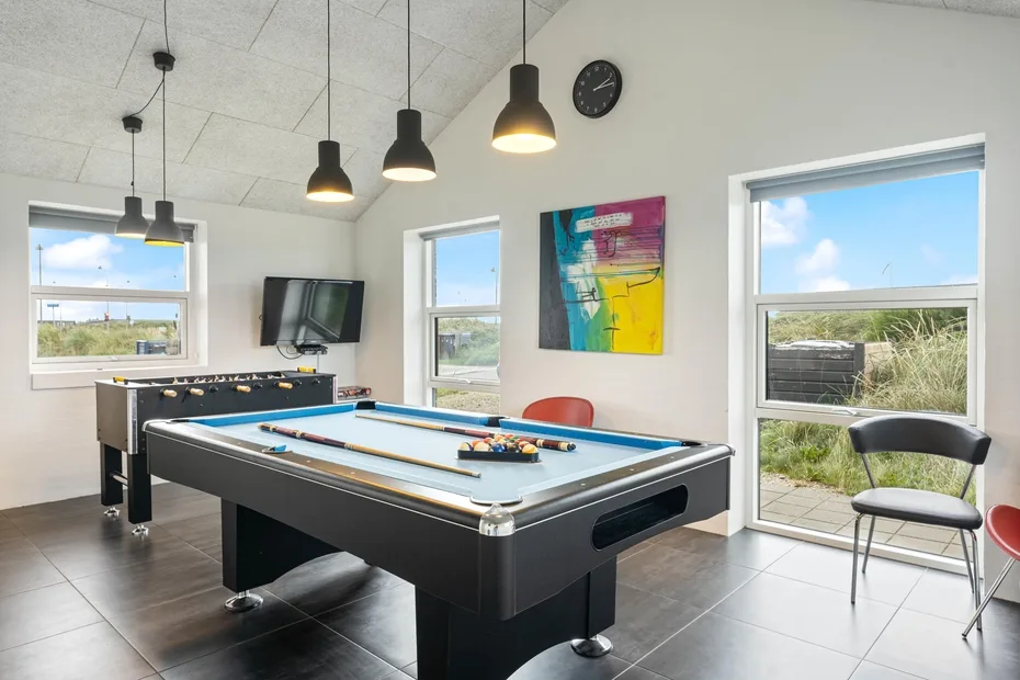 Una luminosa sala de juegos con una mesa de billar y arte colorido en la pared.
