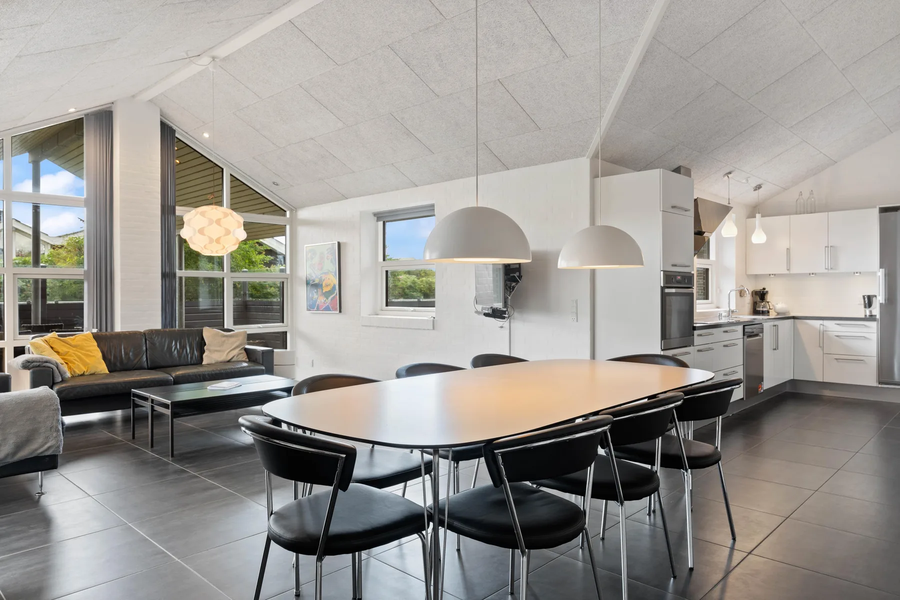 Una sala de estar y comedor de planta abierta con cocina y grandes ventanas.