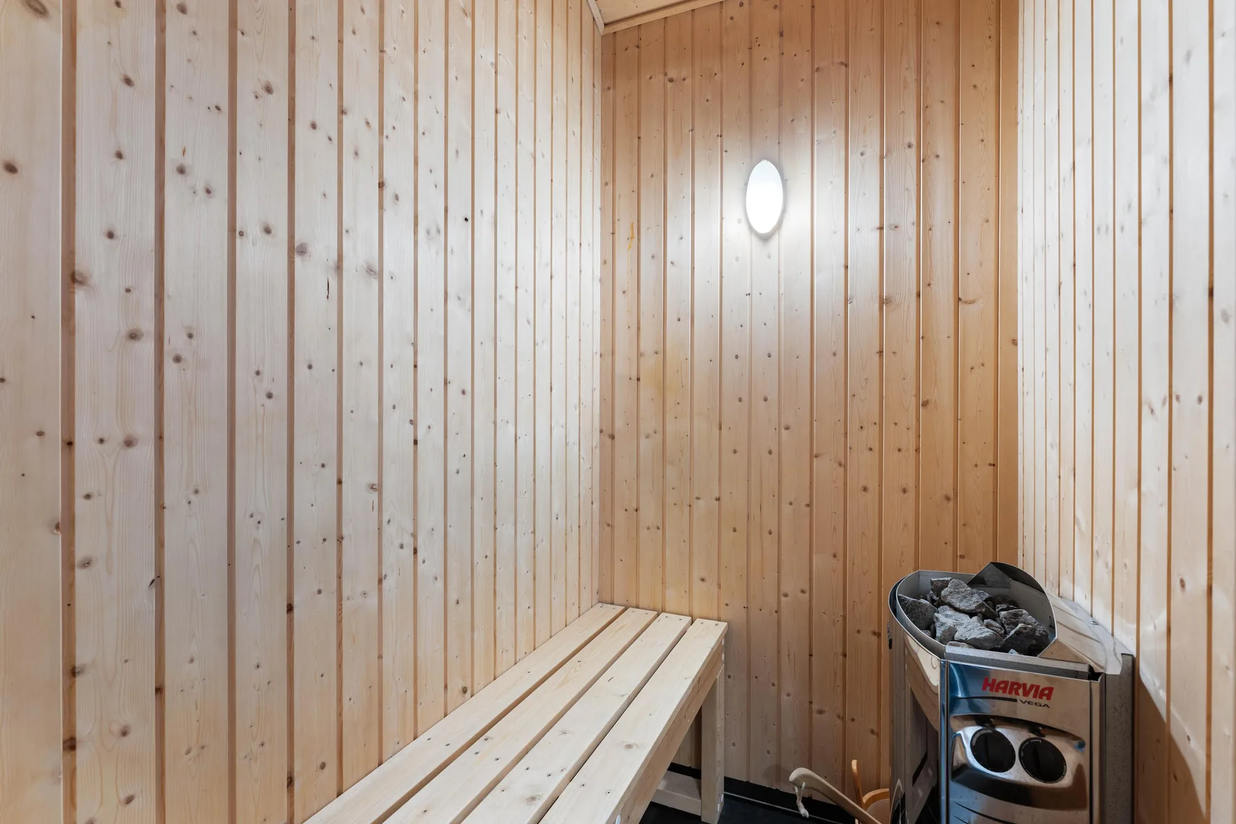 Una sauna revestida de madera con un banco largo y una estufa.