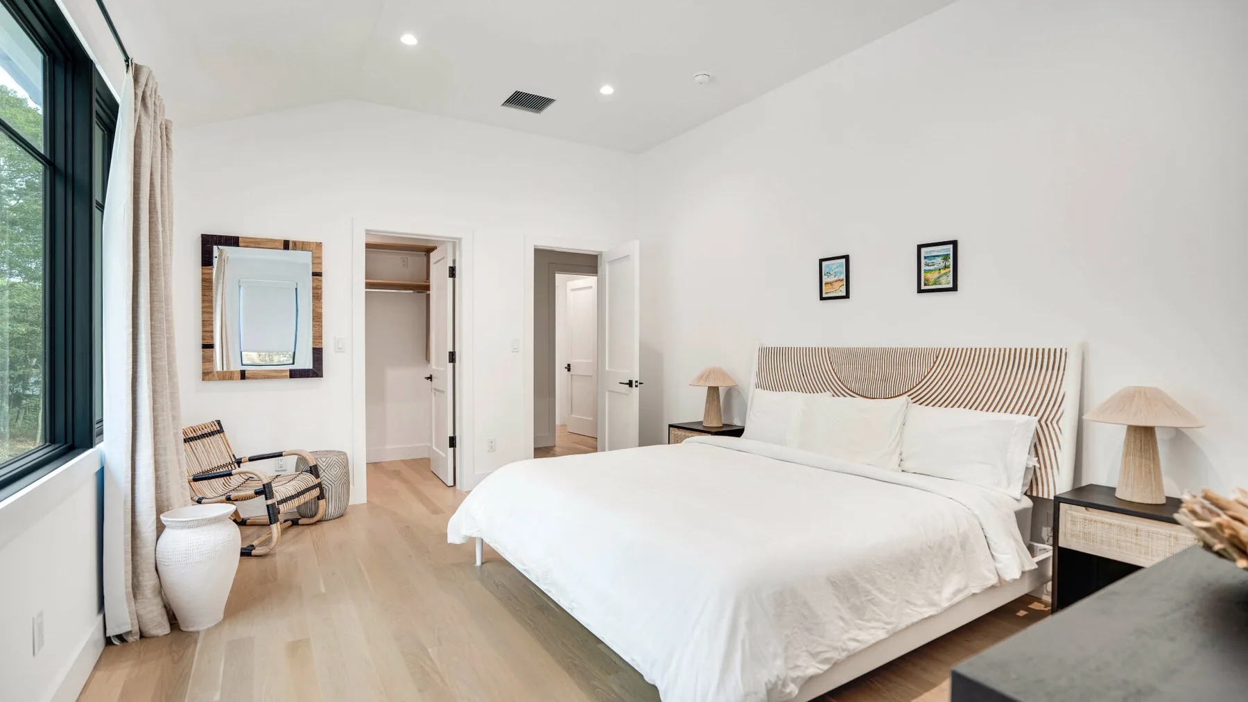 Un dormitorio luminoso con una cama grande junto a una ventana alta.