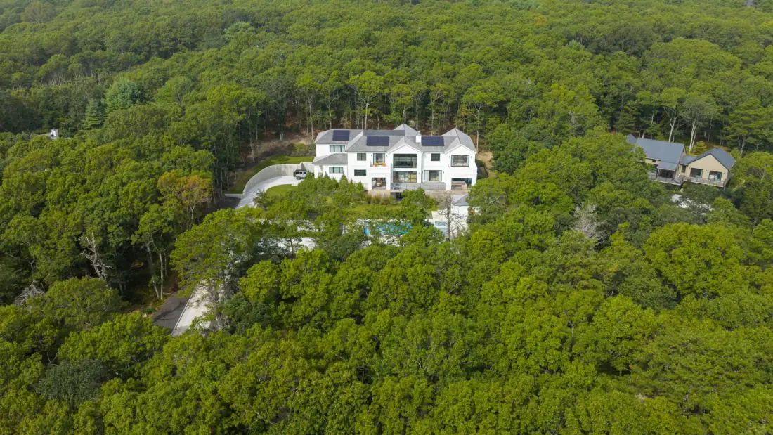 Una casa blanca se encuentra entre árboles verdes en una ladera boscosa.