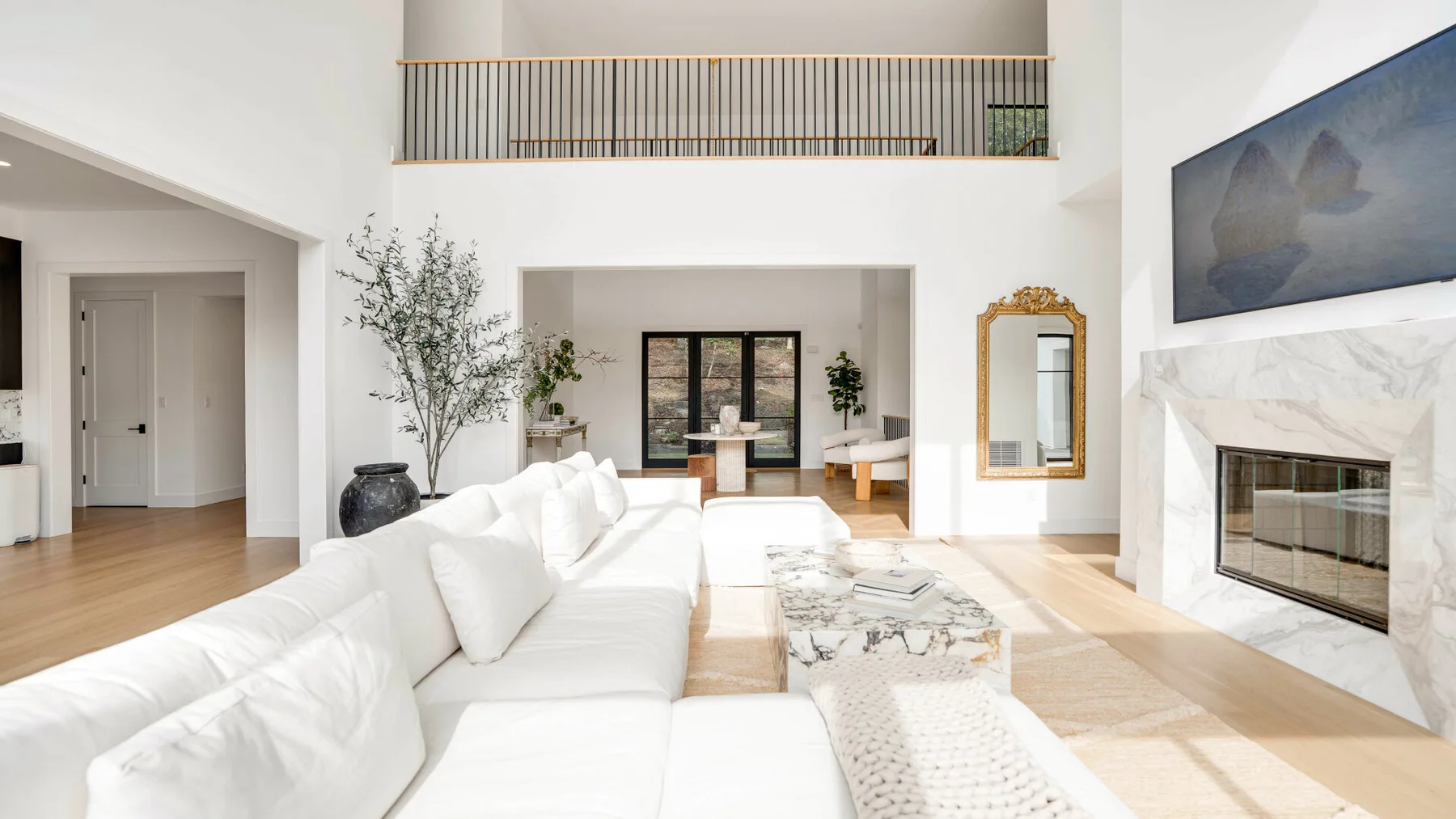 Una sala luminosa con asientos blancos, una chimenea y una barandilla en el nivel superior.