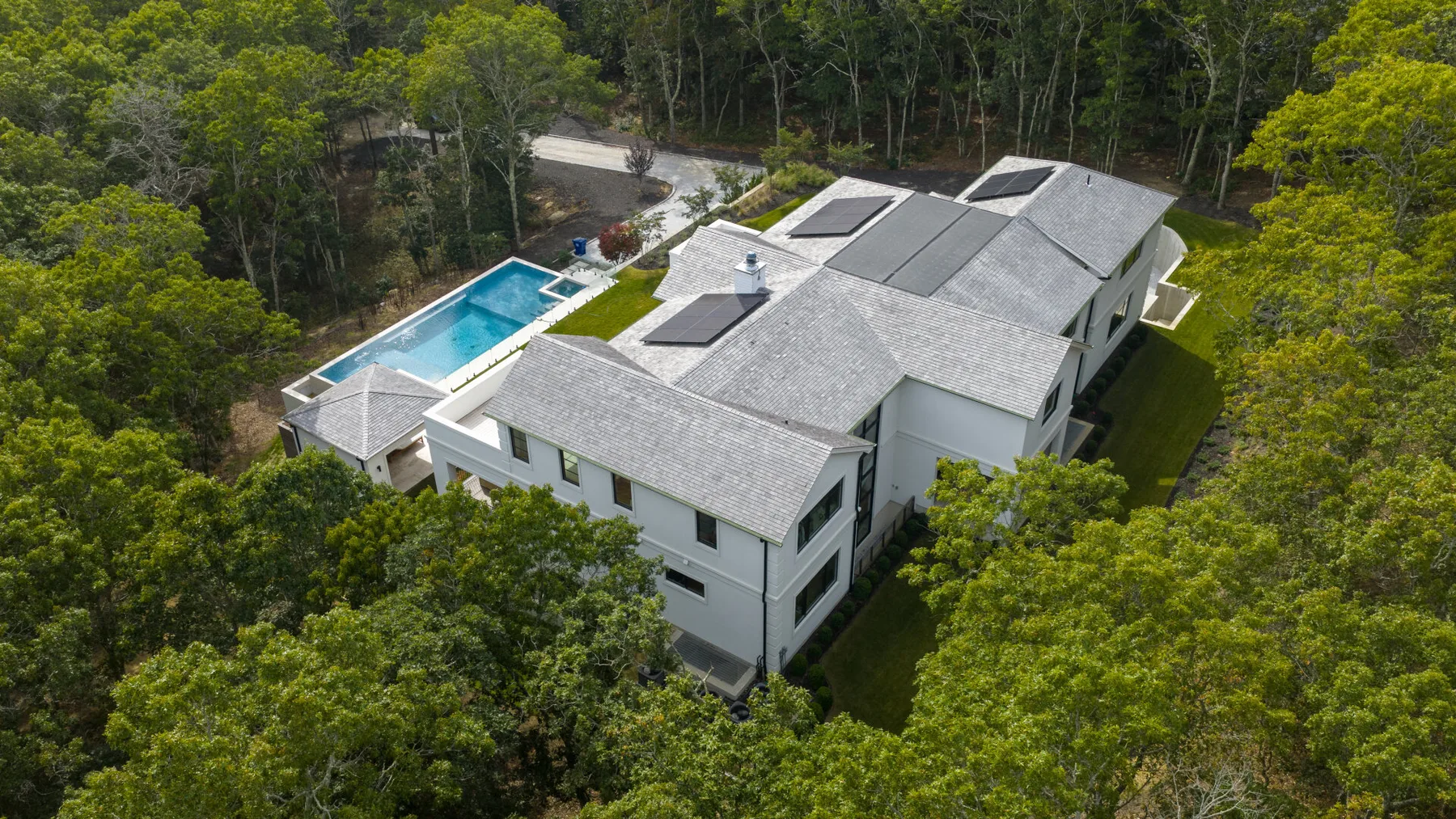 Vista aérea de una casa grande rodeada de árboles, con una piscina.