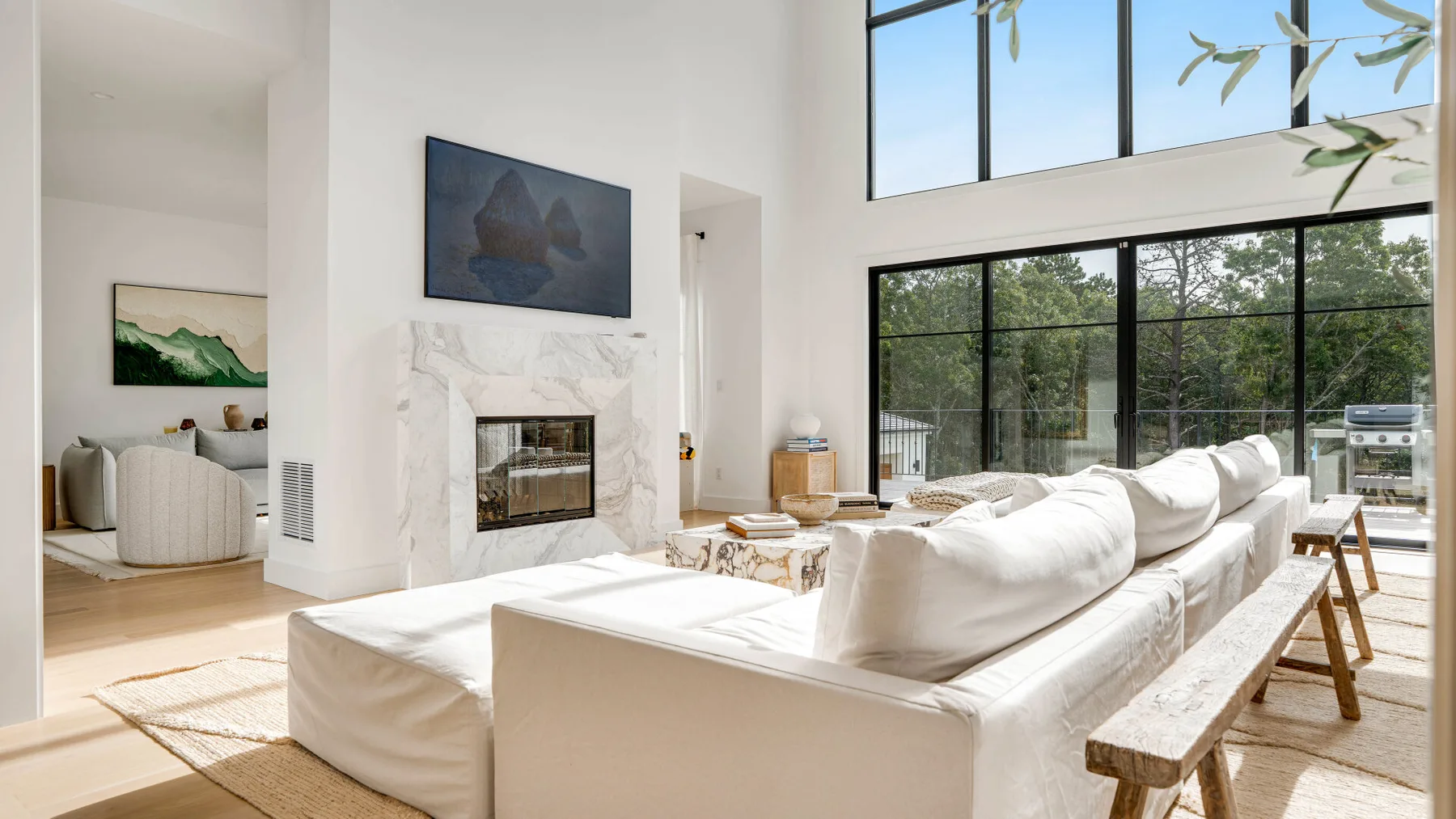 Una sala luminosa con asientos blancos y una chimenea bajo grandes ventanas.