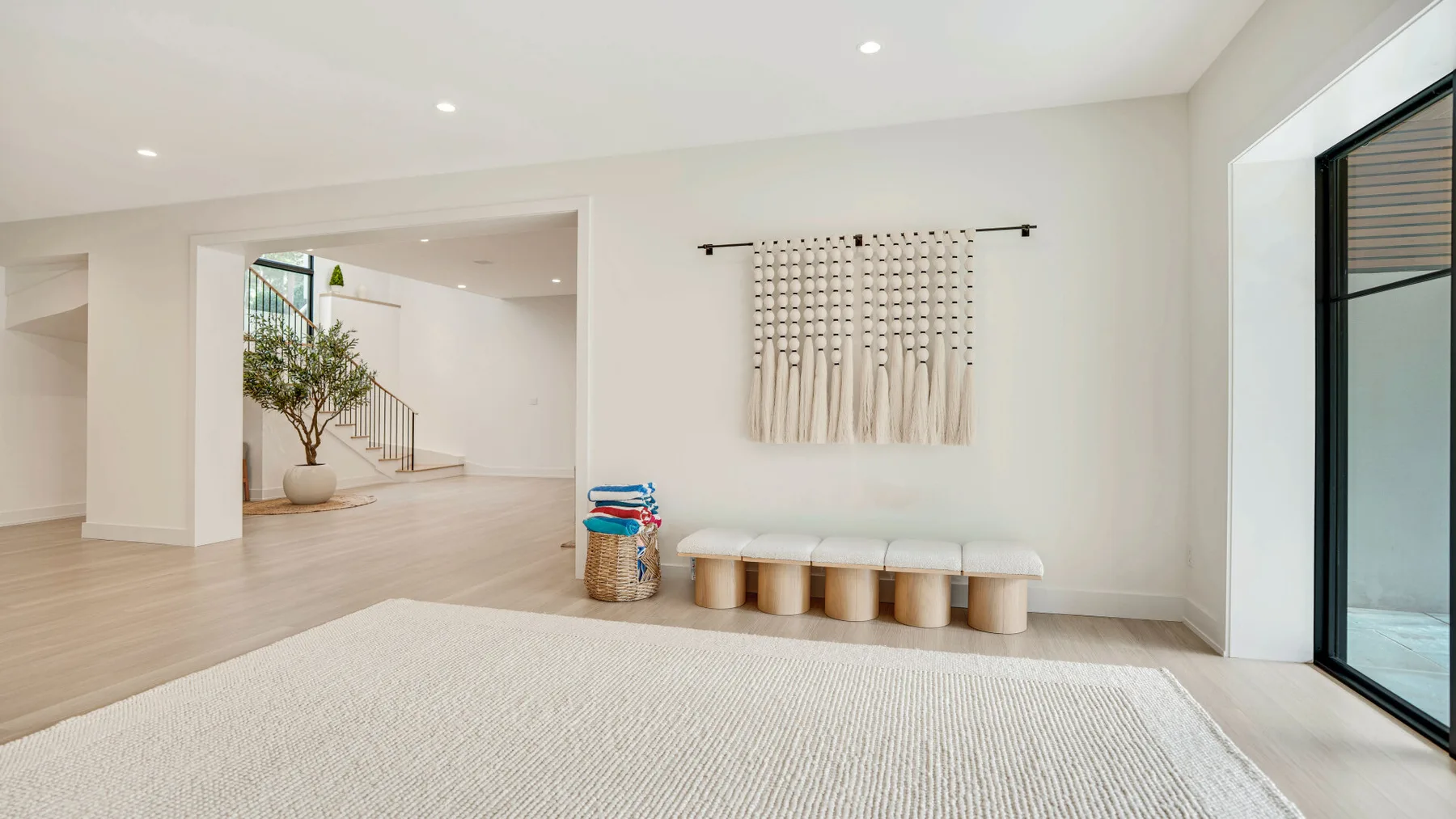 Una sala luminosa con un banco bajo y una alfombra tejida grande.