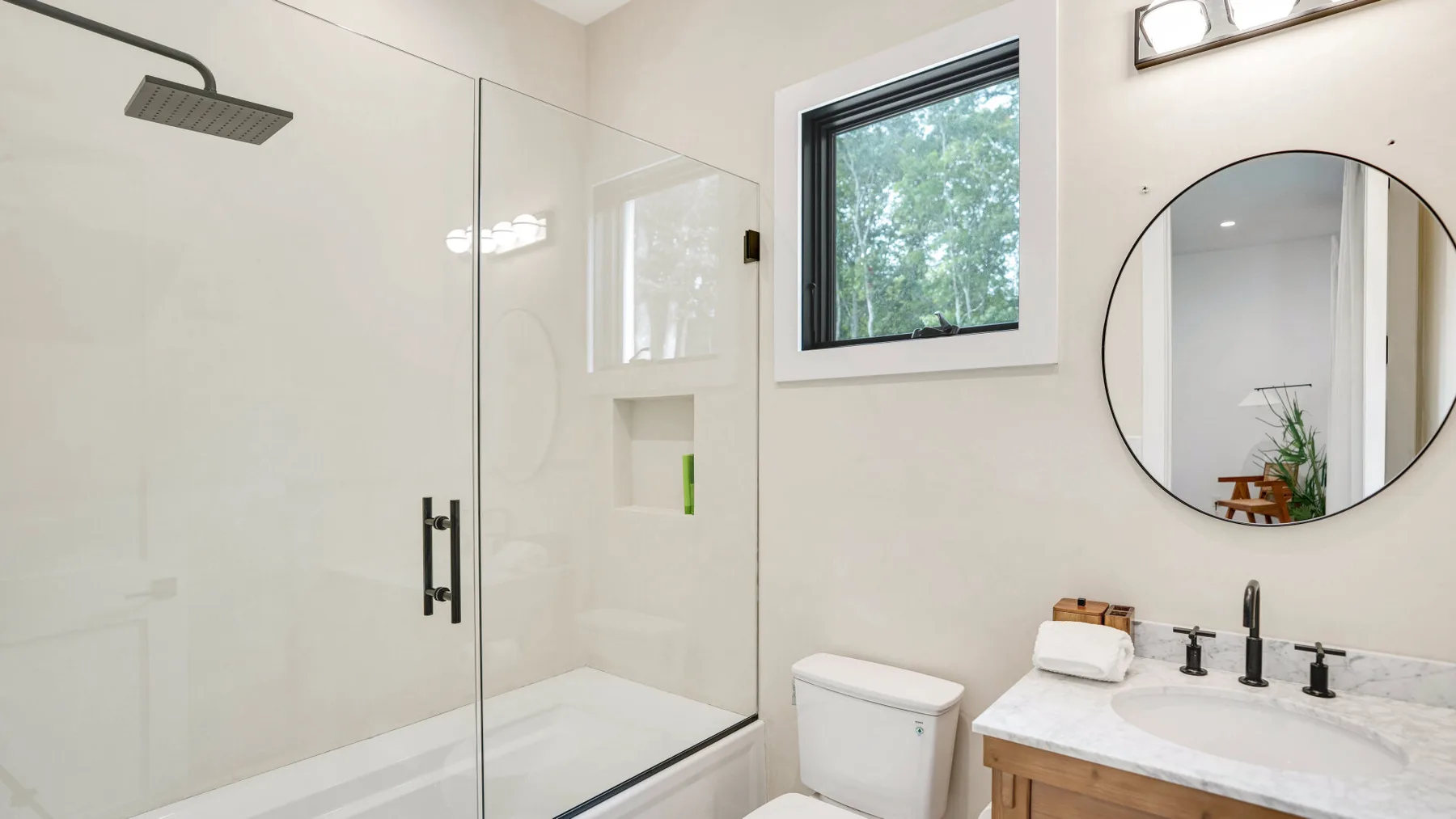Un baño luminoso con ducha de vidrio, lavabo y ventana.