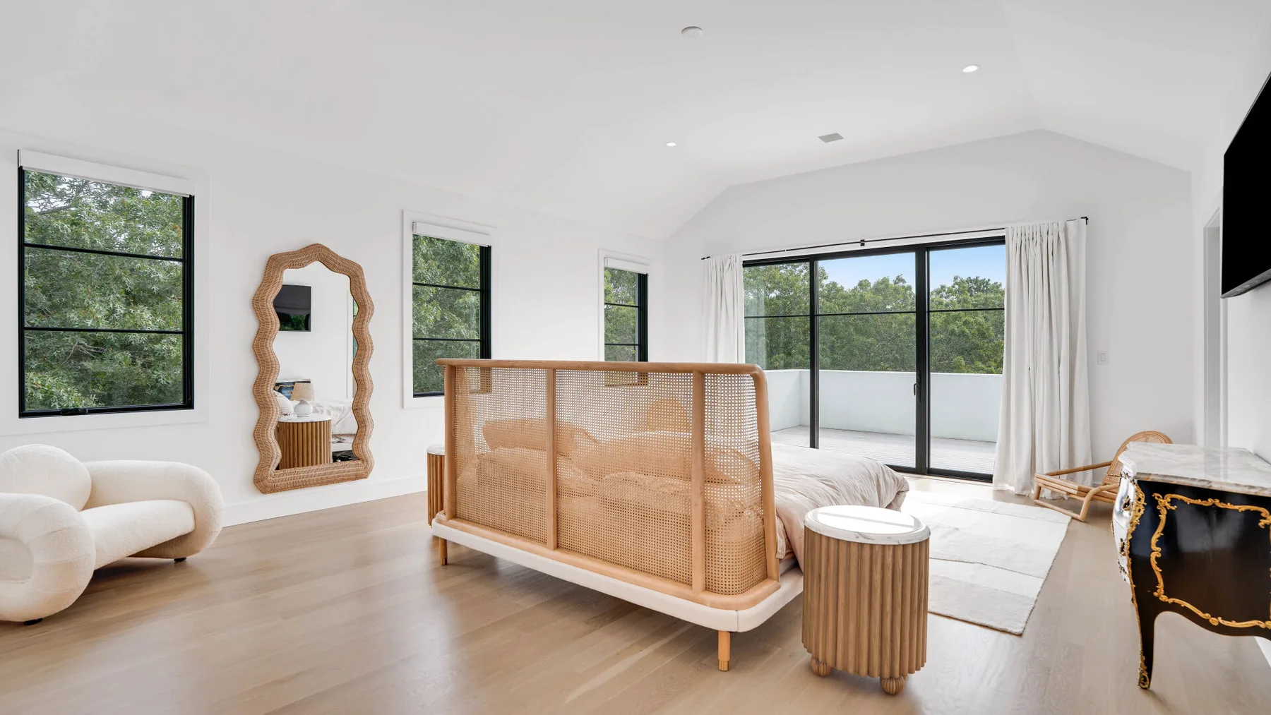 Una sala luminosa con ventanales, una zona baja para sentarse y un biombo tejido.