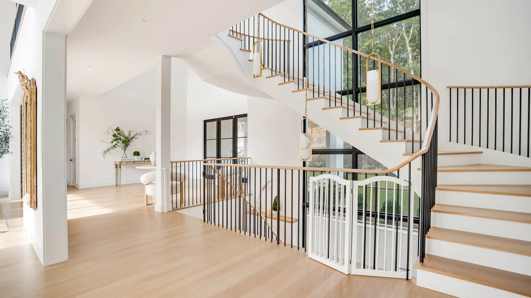 Un pasillo interior luminoso con una escalera y grandes ventanas.