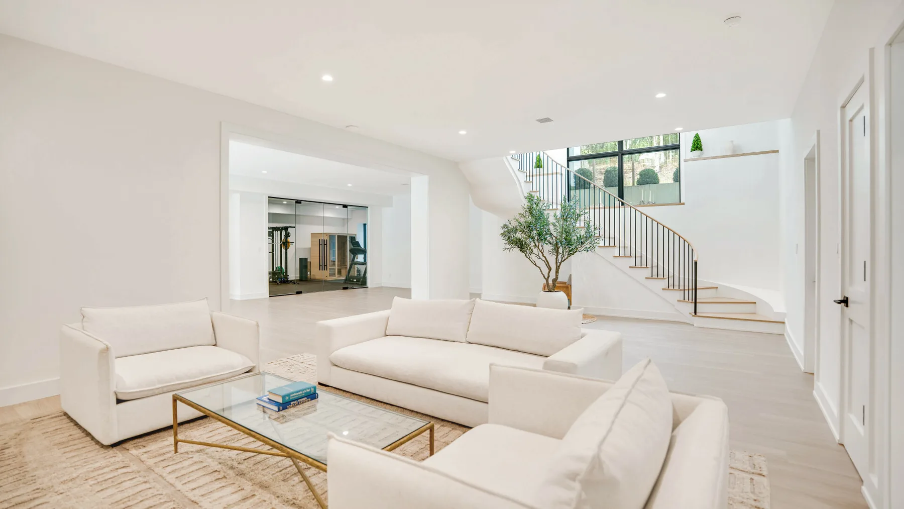 Una sala luminosa con asientos blancos y una escalera al fondo.