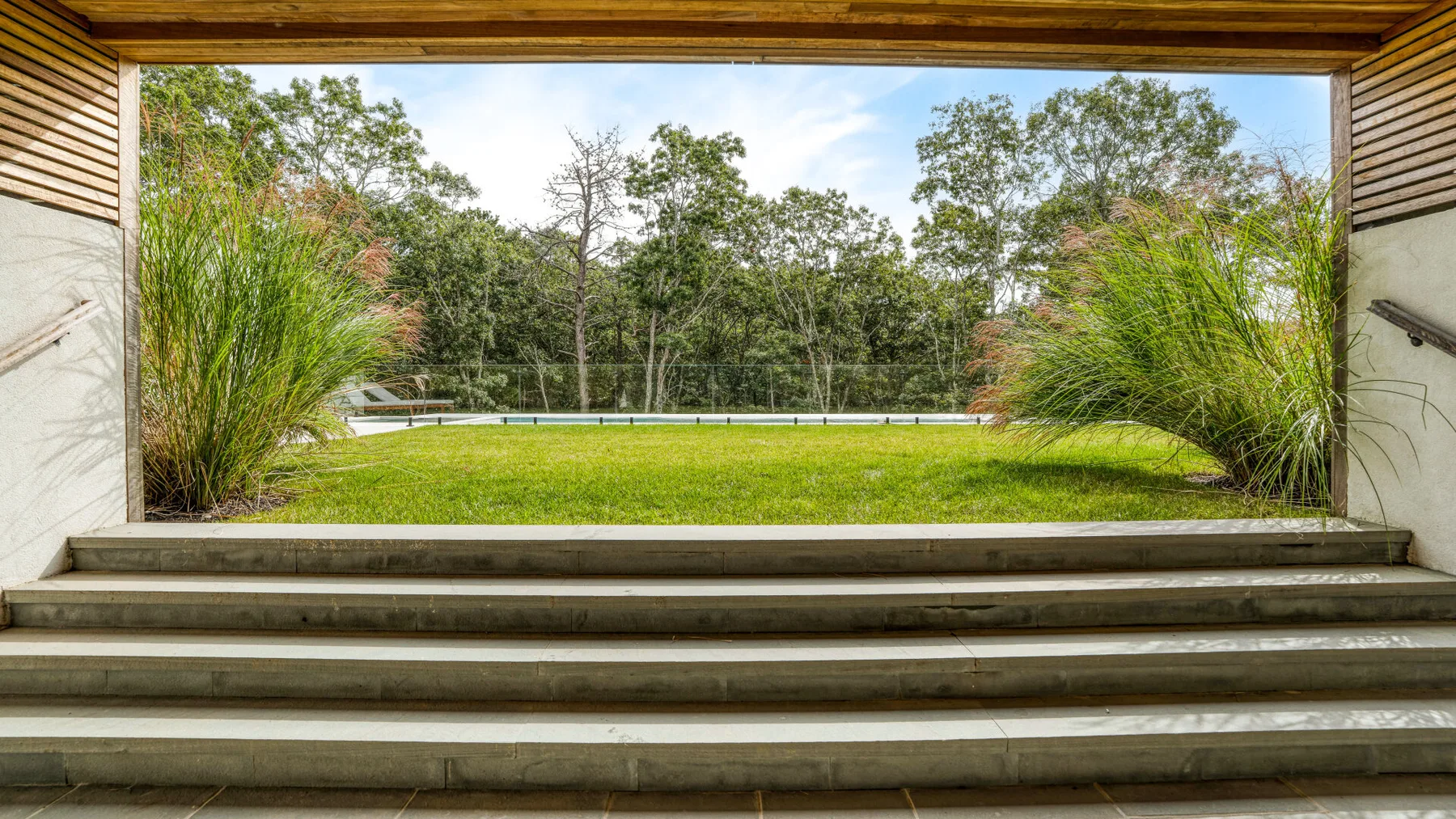 Una terraza al aire libre da a un césped y árboles alrededor.