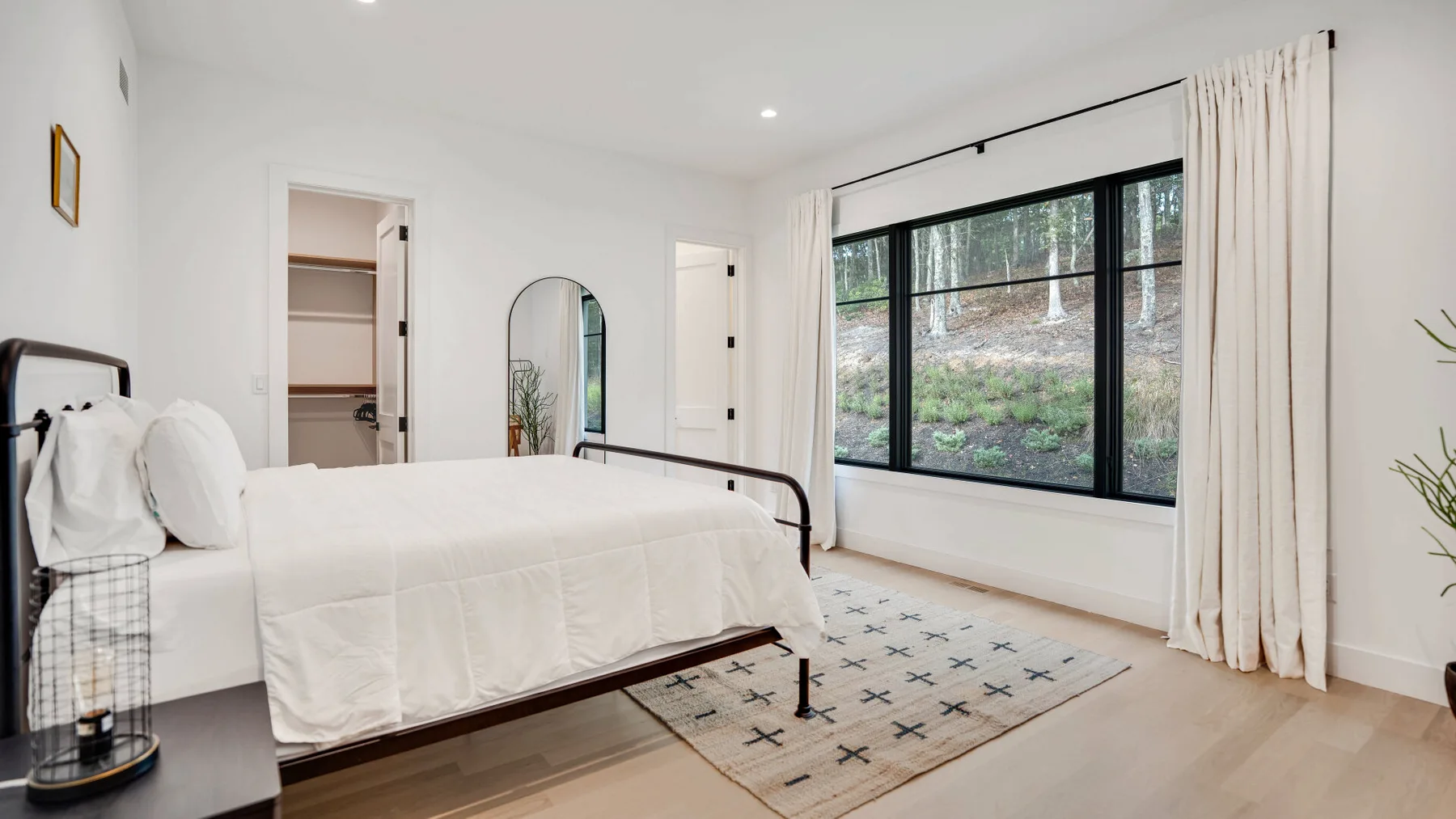 Un dormitorio luminoso con una cama grande junto a una ventana amplia.