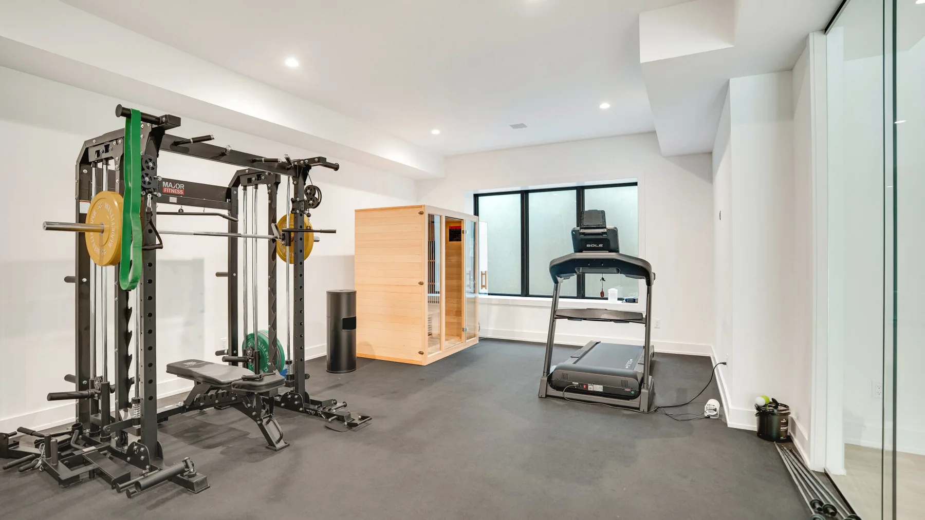 Un gimnasio en casa con equipo de pesas y una caminadora.