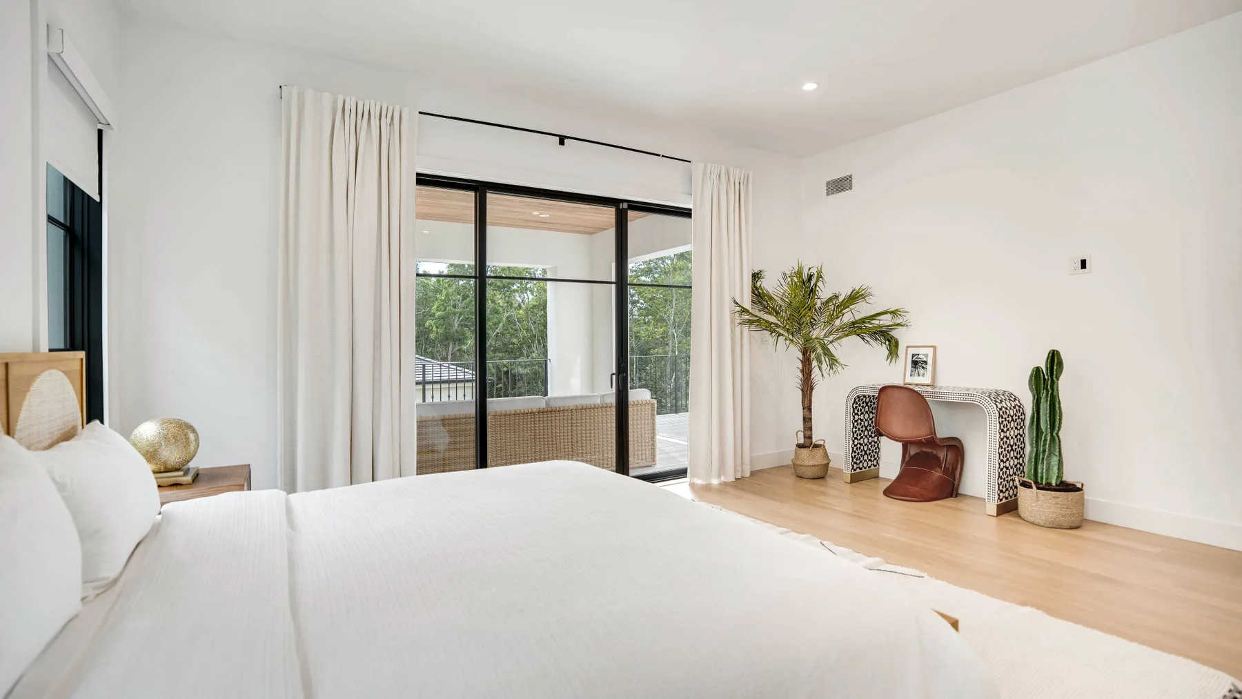 Un dormitorio luminoso con una cama, puertas corredizas de vidrio y un pequeño escritorio.