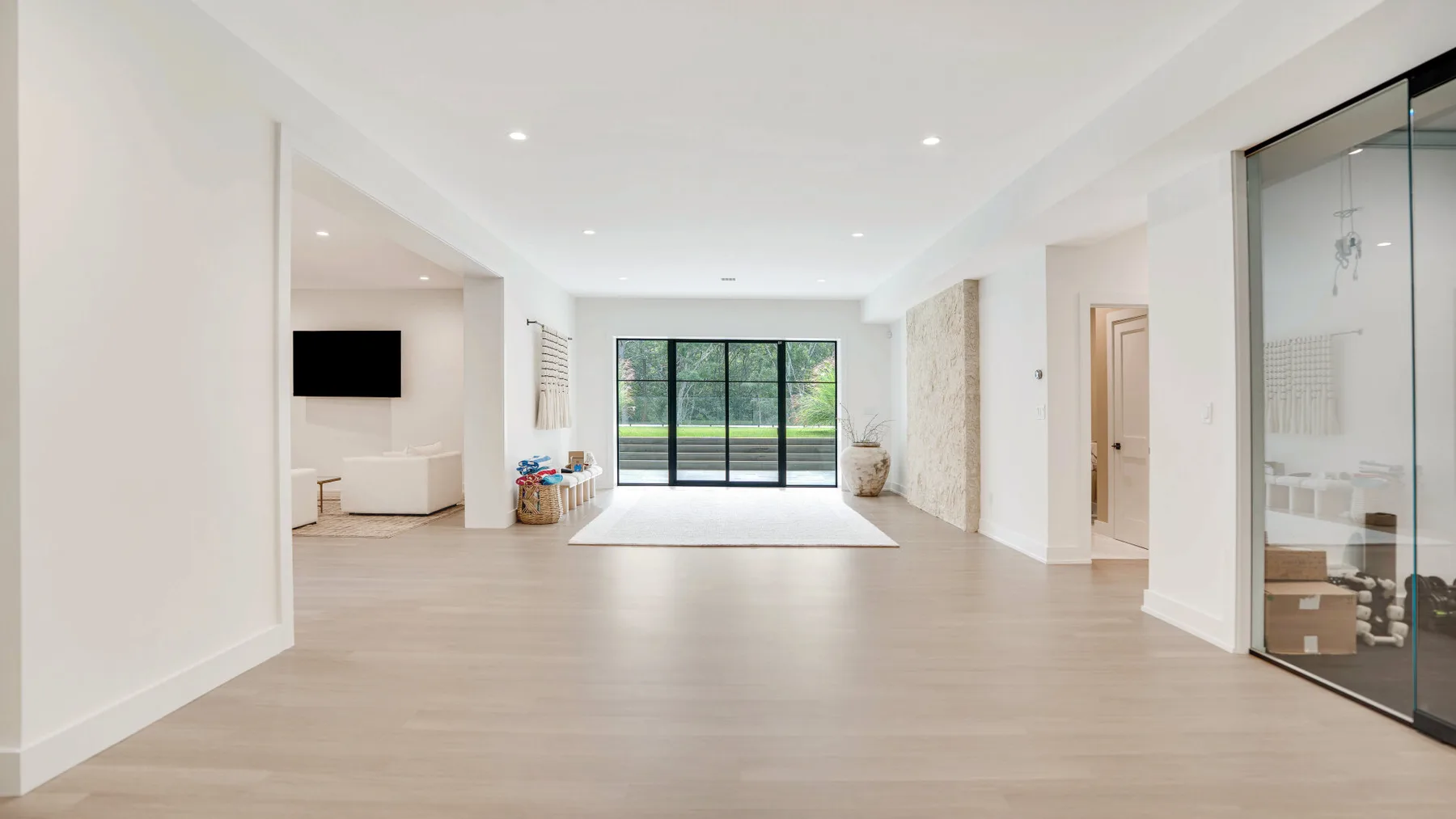 Una luminosa sala de estar abierta con grandes ventanas y una puerta de paneles de vidrio.