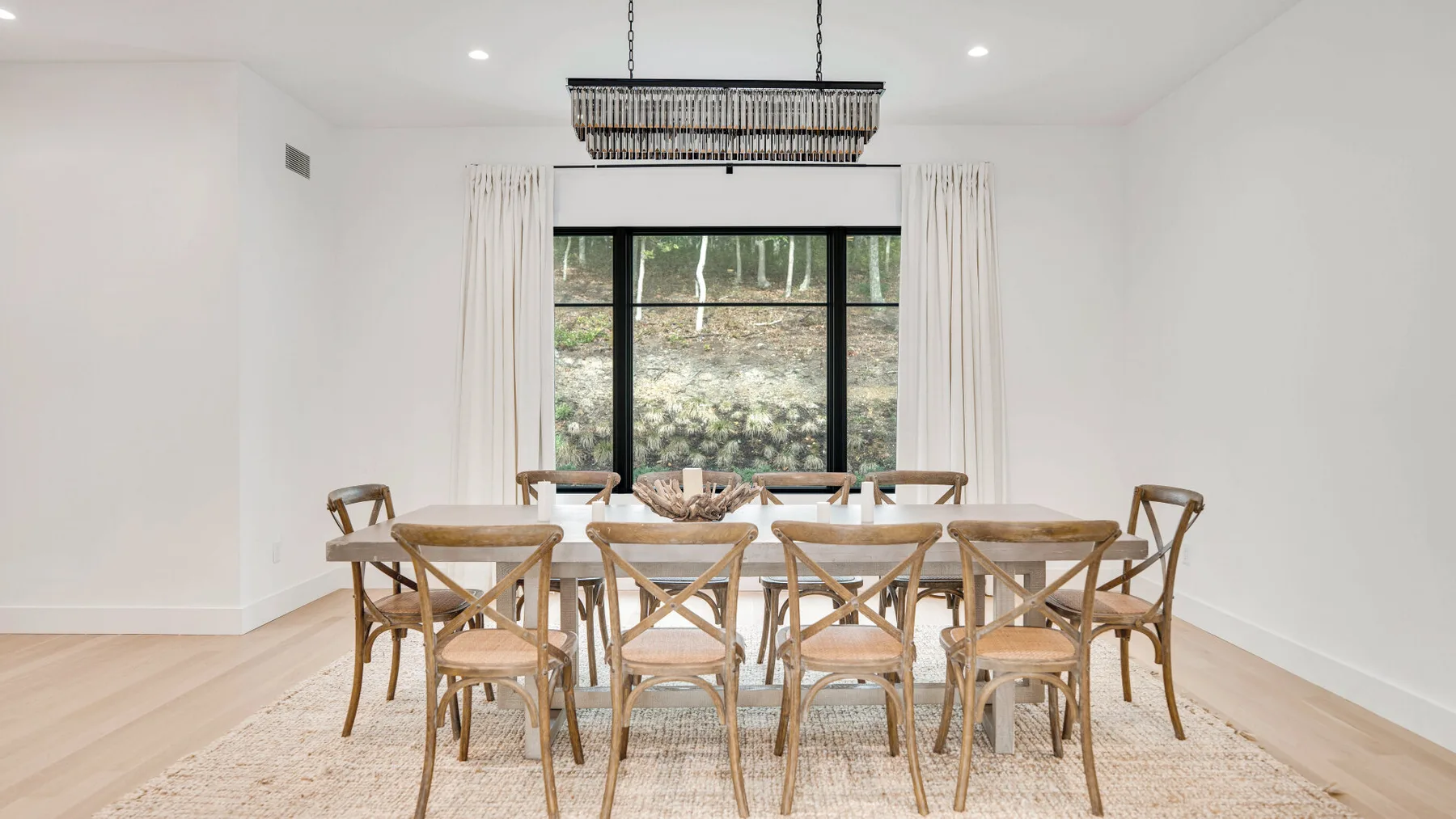 Un comedor con una larga mesa de madera y sillas bajo una lámpara colgante.