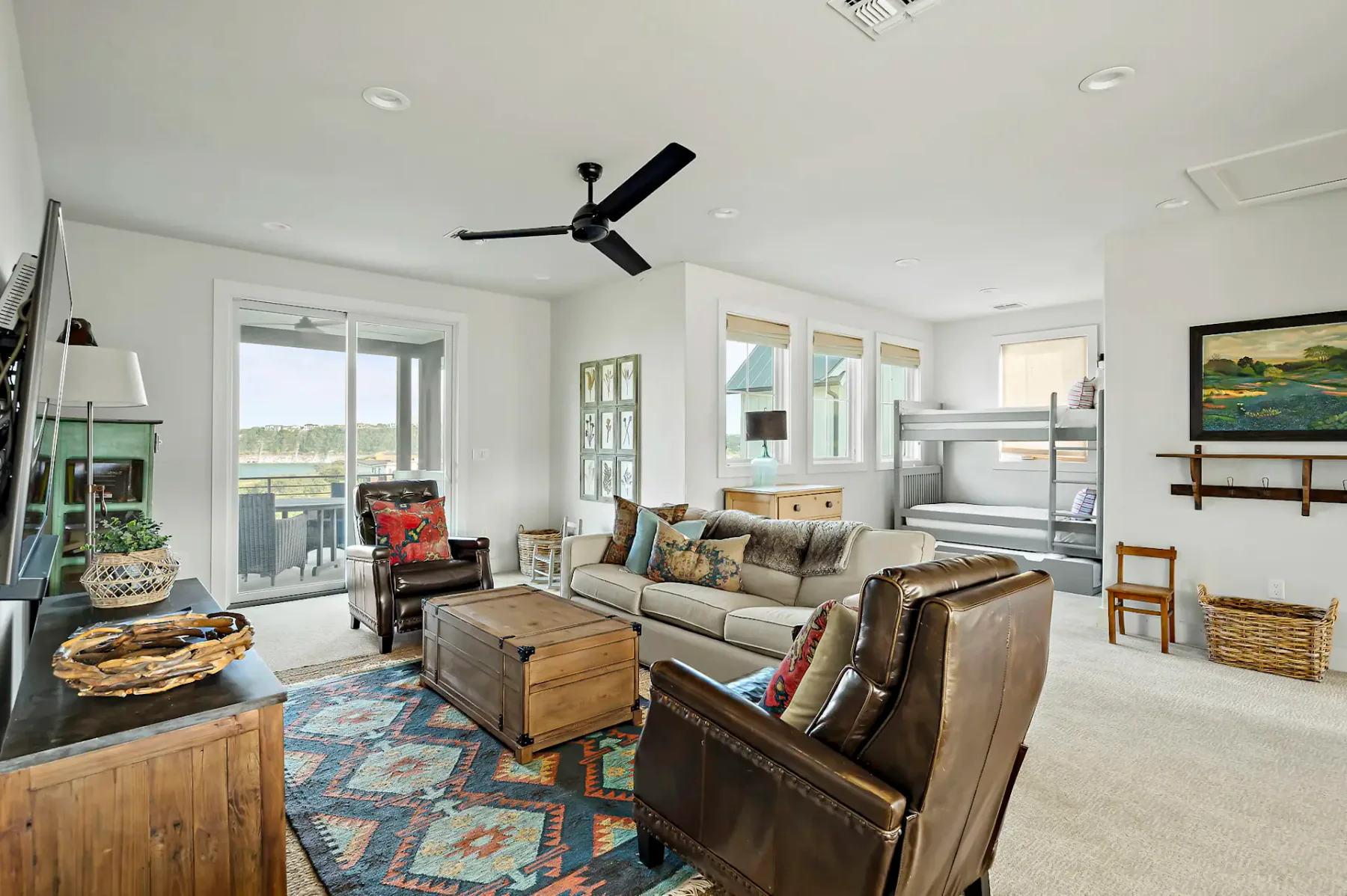 Bright living room with seating arranged around a coffee table and colorful rug.