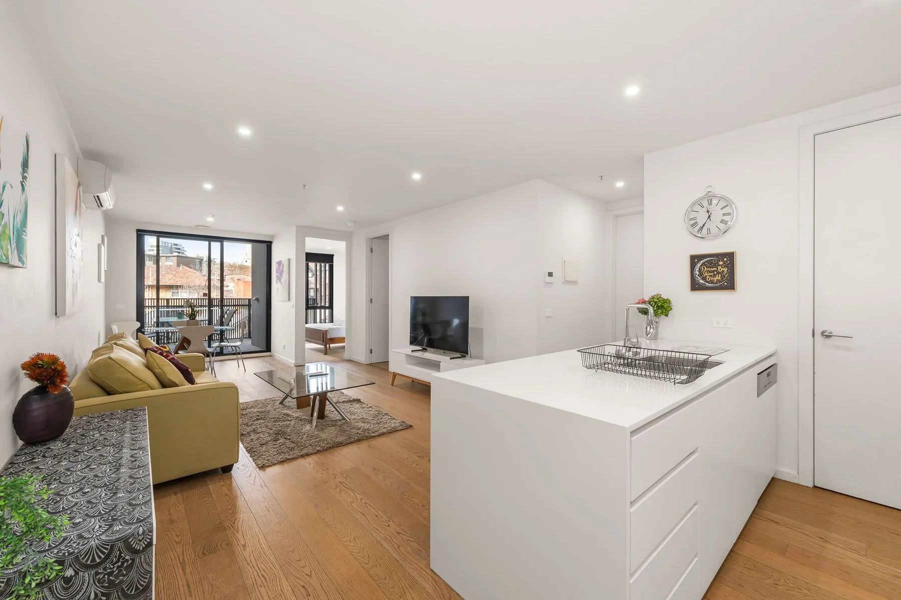 Open-plan living room with a seating area, television, and kitchen island.