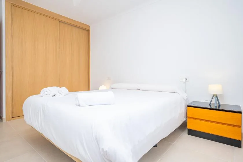 A bedroom with white bedding and a wooden wardrobe.