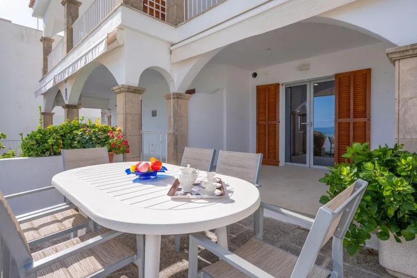 An outdoor patio with a white dining table and sliding glass doors.