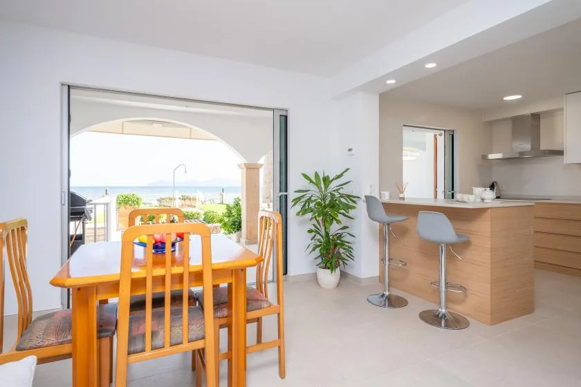 A dining area opens onto a bright kitchen, with a view of the sea outside.