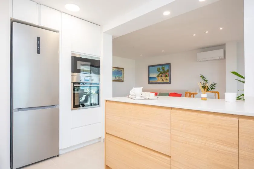 A bright kitchen with stainless-steel appliances and a pale wood island.