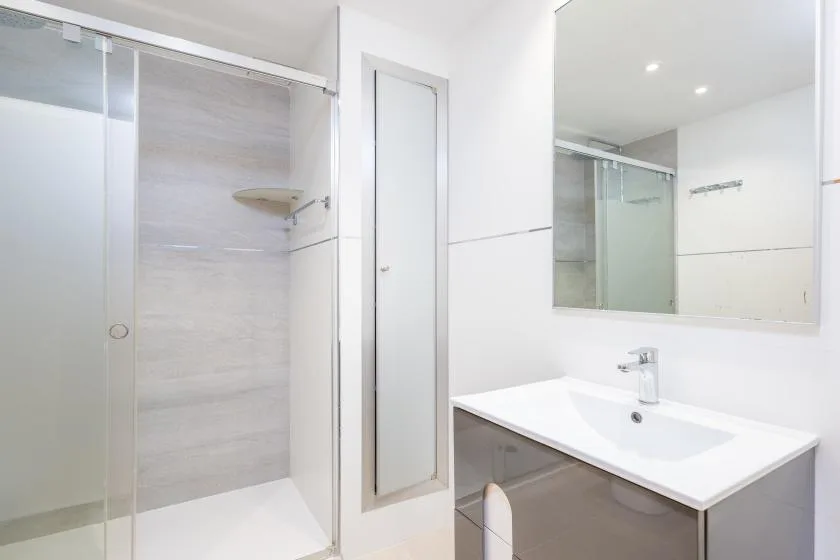 A bright bathroom with a glass shower and a white sink vanity.
