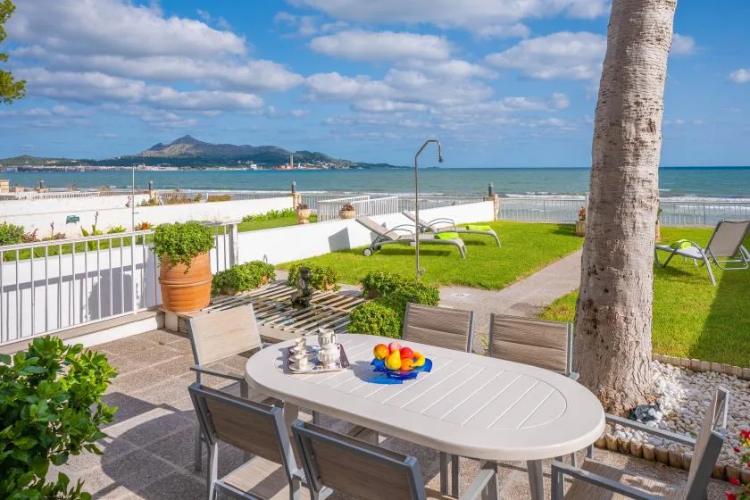 A seaside patio has outdoor seating and a table overlooking the beach.