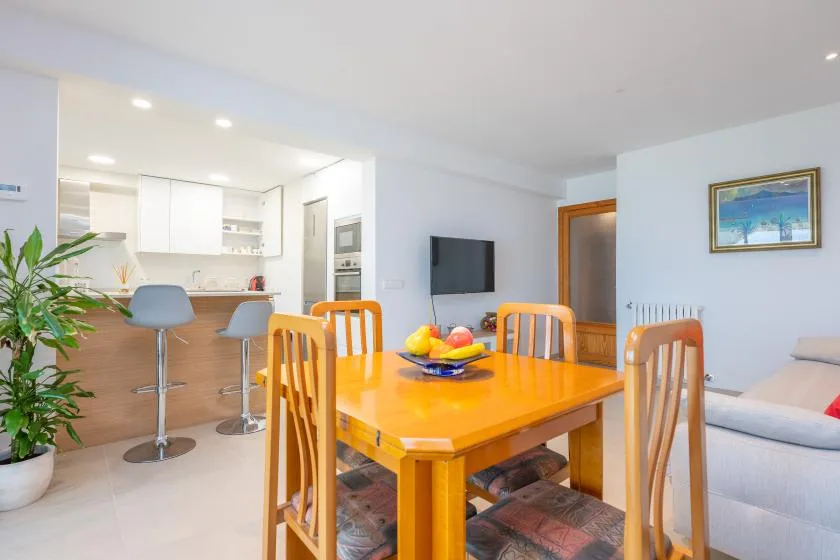 Dining area with a wooden table beside an open kitchen.