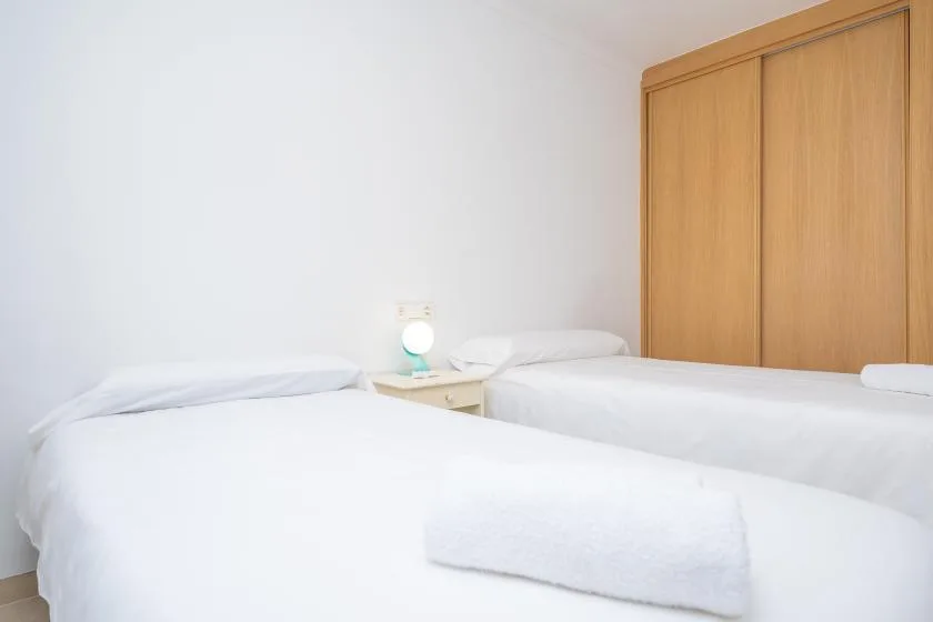 A bedroom with two beds and a wooden wardrobe.