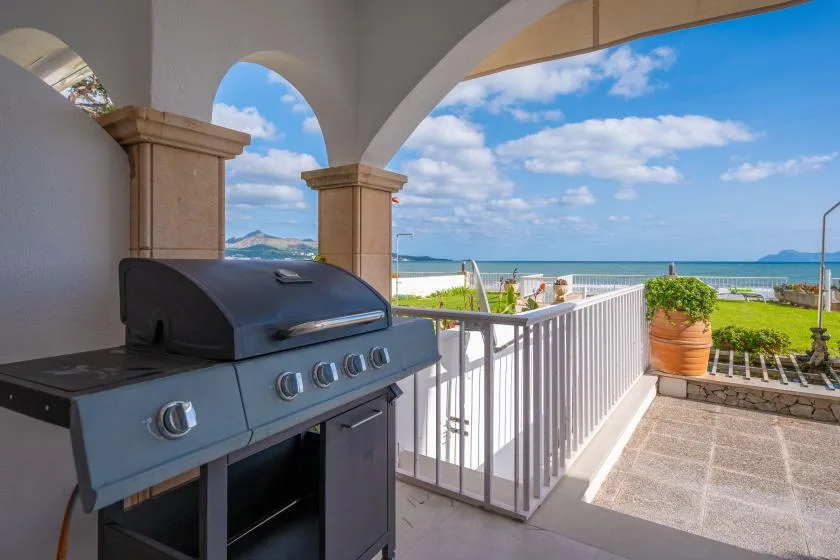 A covered outdoor patio with a barbecue grill and views of the sea.